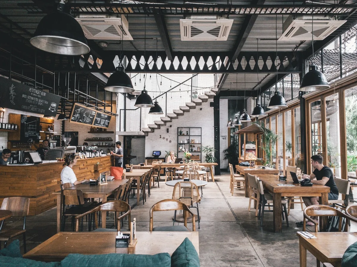 Café dining room with staff at the counter and guests at wooden tables