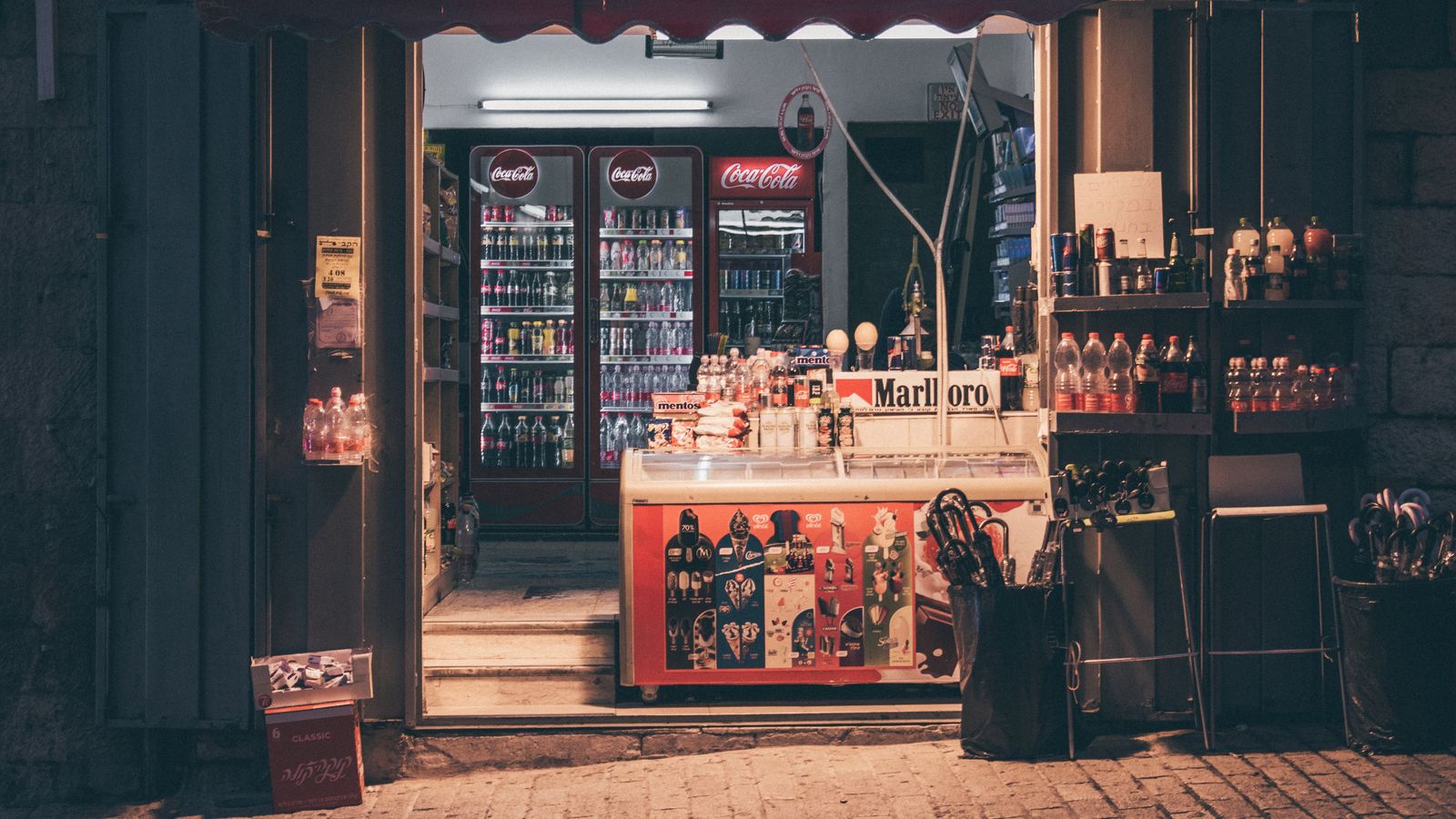 Neighborhood convenience store stocked with drinks and goods at dusk