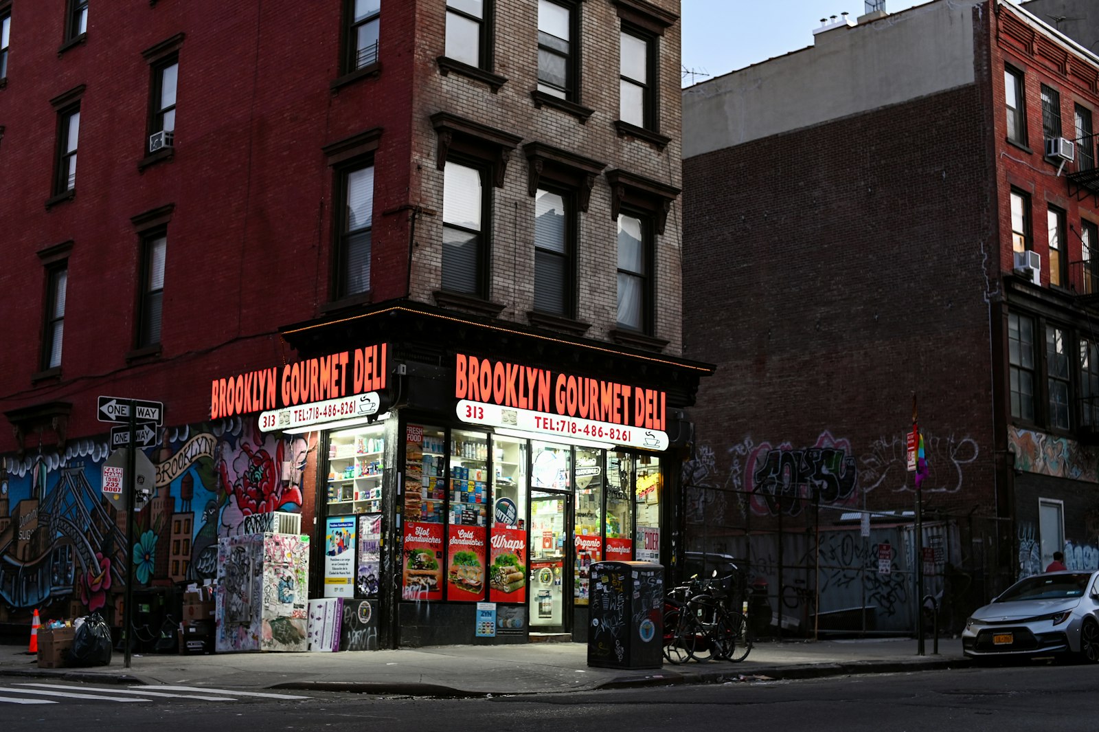 Brooklyn corner deli storefront lit up on a New York City block at dusk